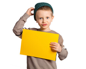 A handsome European boy with blue eyes holds a yellow sheet of paper, makes a funny face, confusion. Place for text, banner, surface for inscriptions and advertising.