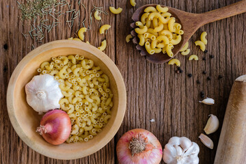 The view of the macaroni on the wooden background is a popular ingredient for cooking. There are many different shapes according to usage.