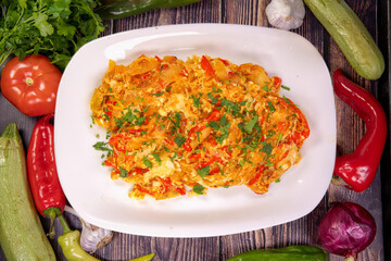 Tasty rustic style eggs with vegetables on a white plate, top view