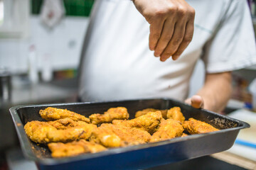 Chef salting freshly prepared fried chicken nuggets. Restaurant meal preparation