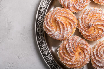 Muffins in powdered sugar served in metal tray. View from above