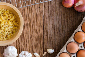 The view of the macaroni on the wooden background is a popular ingredient for cooking. There are many different shapes according to usage.