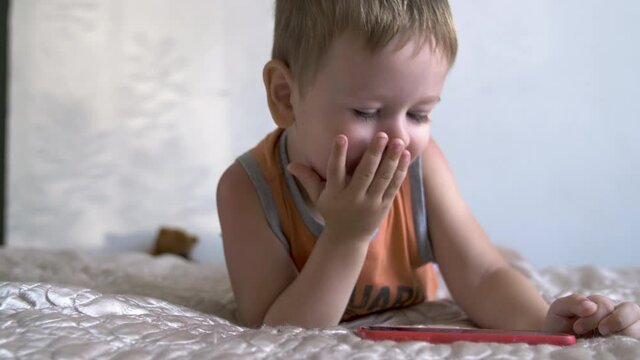child boy watch play smartphone on bed at home. distance learning education