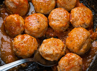 Cooking meatballs with tomato sauce in black pan. Flat lay, top view.