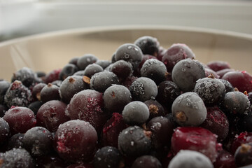 Frozen berries in a plate. Fresh frozen cherries and currants. Berries covered with frost