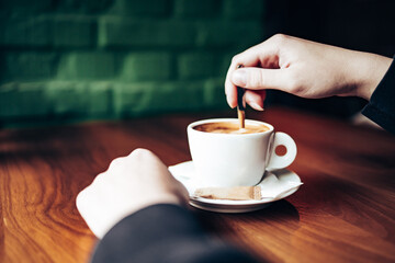 Close-up of customers hands and fresh cappuccino on the table