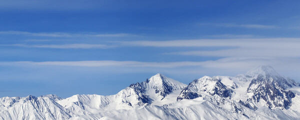 Panoramic view on high snowy mountains and blue sky with clouds