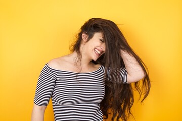 Shot of happy young woman with positive smile, has long hair, rejoices having weekend and good rest after hard working exhausting week, isolated on gray wall.