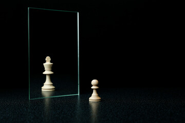 reassessment of their abilities. the pawn is reflected in the mirror like a king on black background - obrazy, fototapety, plakaty