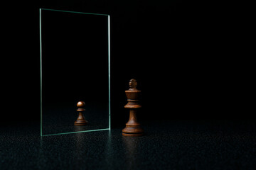 the king is reflected in the mirror as a pawn on black background. underestimation of their...