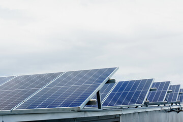 Naklejka premium Solar panels stands in row on the roof . Free electricity for home. Sustainability of planet. Green energy. Solar cells power plant business. Ecological clean energy. Blue panels on the ground.