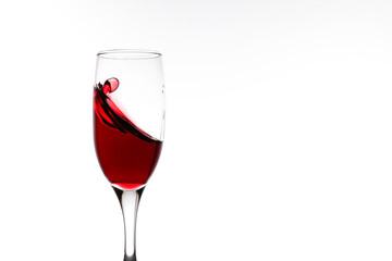 red wine is splashing in a glass on white background