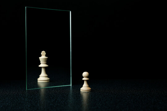 reassessment of their abilities. the pawn is reflected in the mirror like a king on black background