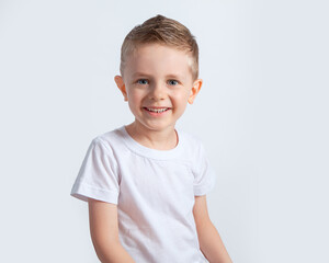A beautiful European boy in a white t-shirt on a white background. A blue-eyed child of five years...
