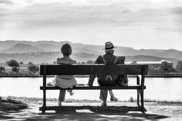 A beautiful old couple contemplates the future, sitting together, overlooking a beautiful and picturesque lake.