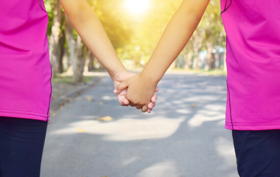 Two children holding hands in the street with the sun shining. - Powered by Adobe
