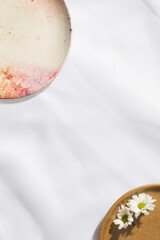 Top view of white flowers in a plate and a empty plate in voile fabric background with space for text.