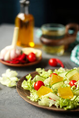 on a gray table is a plate with salad, marmalade of olive oil, tomatoes and cucumbers.
