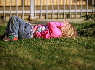 Beautiful child girl blonde walks in the summer in the sun in the green grass