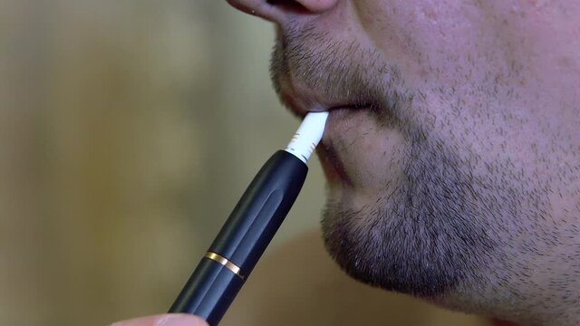 Unshaven man smokes an electronic cigarette