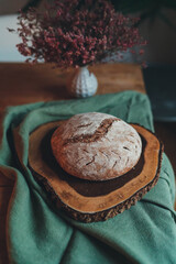 Homemade sourdough bread, Round loaf of freshly baked homemade artisan sourdough bread on a round wood plank, Cooking at home concept