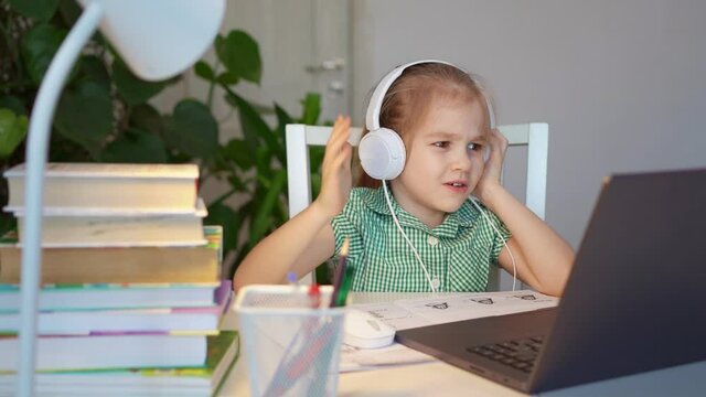kid girl in headphones listens to lesson, distance online learning home