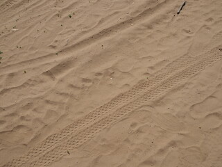 various tracks in the sand - tires from cars, bicycles and human shoes