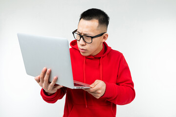 attractive brunette man in casual red hoodie with a laptop in his hands on a white studio background