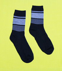 A pair of black men's socks on a yellow background