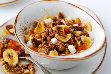Authentic muesli and a cup of tea sprinkled with cinnamon on a white tablecloth. Morning atmospheric lighting, fashionable trendy spot soft focus. Preparation for design creative menu.