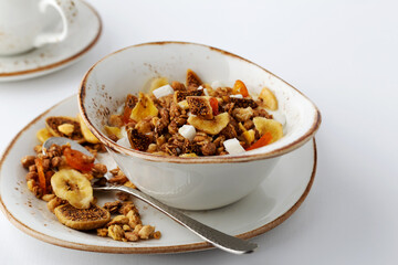 Authentic muesli and a cup of tea sprinkled with cinnamon on a white tablecloth. Morning atmospheric lighting, fashionable trendy spot soft focus. Preparation for design creative menu.