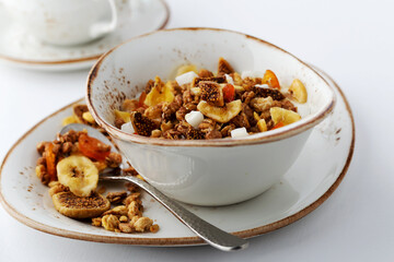 Authentic muesli and a cup of tea sprinkled with cinnamon on a white tablecloth. Morning atmospheric lighting, fashionable trendy spot soft focus. Preparation for design creative menu.