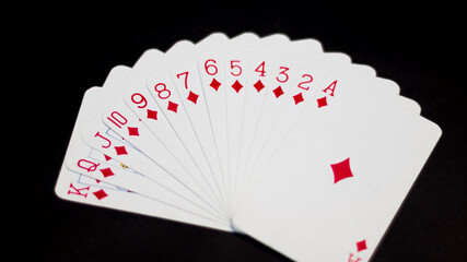 Juego de cartas de poker con un ángulo levemente elevado sobre un fondo negro e iluminación directa sobre ellas. Juego de cartas de diamantes aislados.