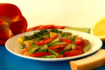 Stewed potatoes with vegetable salad of cucumber and bell pepper on a white plate. Side view..