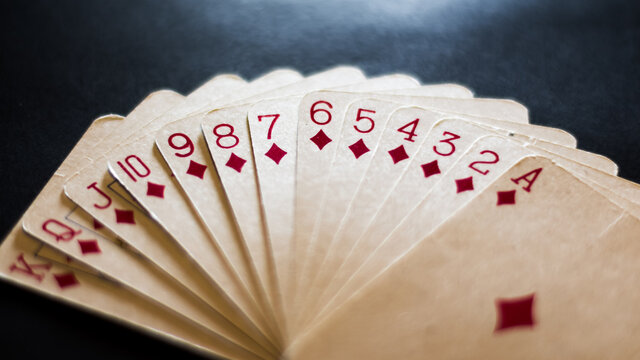Juego de cartas de poker con un &aacute;ngulo levemente elevado sobre un fondo negro e iluminaci&oacute;n directa sobre ellas. Juego de cartas de diamantes aislados.