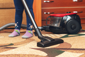 A small child vacuums a carpet with a vacuum cleaner