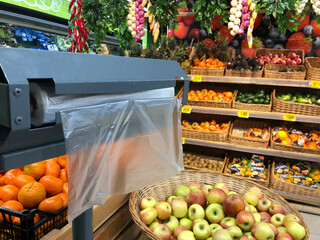 transparent plastic bags hang in roll in rack in grocery store for packing fruits and vegetables. Harmful unecological packing concept.