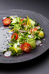 Authentic fresh vegetable salad with sprouts and peas black pepper on a black plate. Morning atmospheric lighting, fashionable trendy spot soft focus. Preparation for design creative menu.
