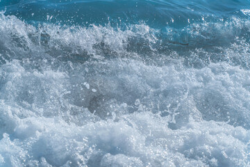 Texture Light blue surface of raging sea water with white foam and wave pattern.The azure surface of the ocean. Waves break at the shore. Natural background.