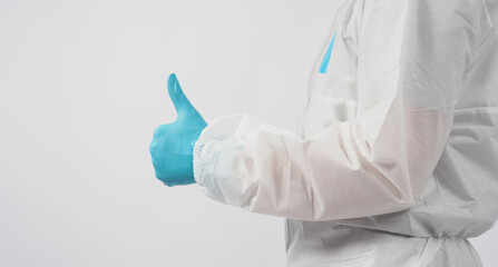 male asian doctor  in PPE suite or Personal Protective Equipment and medical face mask to protect virus doing thumbs up hand sign on white background.