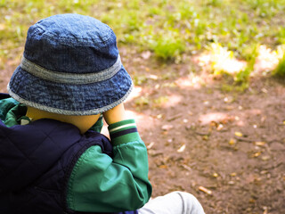 a little boy in a blue vest and Panama hat is crying in the Park side view . sad emotions