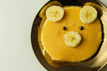Creative meal for a child, pancake with banana and chocolate  in a face little bear  shape