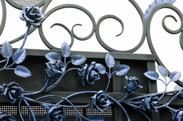 Beautiful forged roses in cold colors on a metal fence