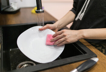 Young woman wash dishes and glass at kitchen
