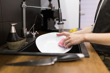 Young woman wash dishes and glass at kitchen
