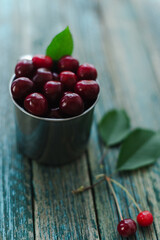 Cherries in a steel mug on a wooden background