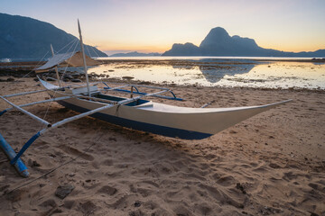 Tropical colorful sunset with a local banca boat in El Nido, Palawan - Philippines