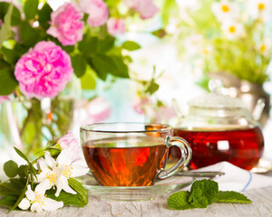 Cup of hot tea and field of flowers on a sunny day