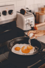 Breakfast preparation. Making morning meal. Weekday routine. Cooking food before work for family. Cracking the eggs into the pan. Home lifestyle. Brunch with husband. Stove, toaster. Selective focus