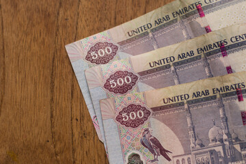 The Currency of the United Arab Emirates (UAE) - Close up of row of purple five hundred Dirham note  on a brown table background. Money exchange.
